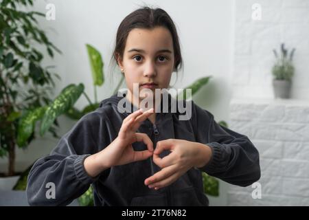 Wunderschönes, lächelndes, taubes Mädchen, das Gebärdensprache benutzt. Stockfoto