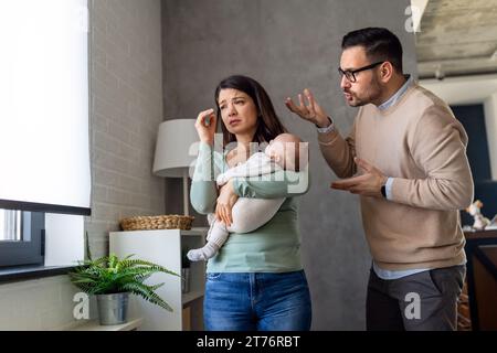 Junger Vater mit Baby und Frau, die zu Hause an postnataler Depression leidet Stockfoto