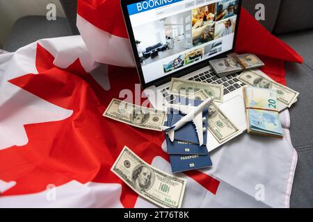 Reise-Laptop, Geld und kanadische Flagge Stockfoto