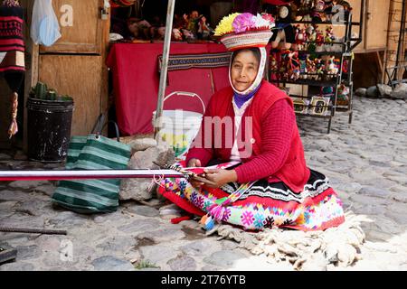 Eine Frau in traditioneller peruanischer Kleidung, die Wolle auf dem Markt webt. Ollantaytambo, Peru, 5. Oktober 2023. Stockfoto