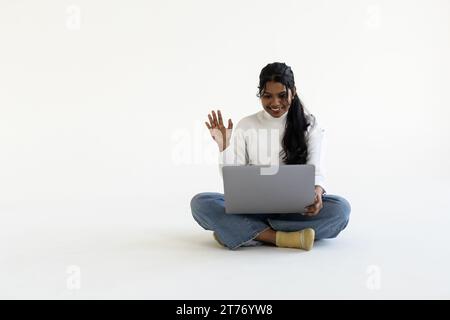 Indische Frau, die Laptop auf weißem Hintergrund benutzt. Stockfoto