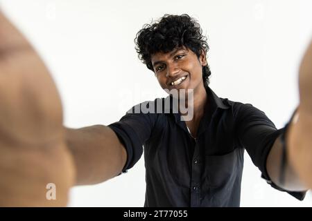 Indischer junger Mann, der Selfie mit Smartphone über weißem Hintergrund macht Stockfoto