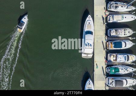 Blick aus der Vogelperspektive auf Luxusyachten, die auf einem trüben Fluss in den Docklands in Melbourne, Victoria, Australien, liegen. Stockfoto