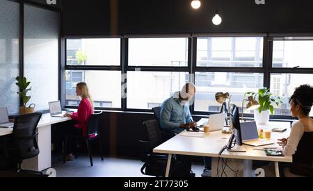 Viele verschiedene weibliche und männliche Kollegen sitzen am Schreibtisch und nutzen Laptops im Büro Stockfoto