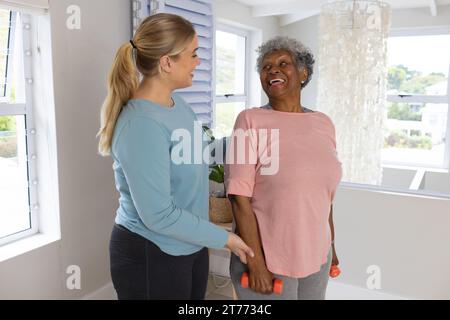 Kaukasische Physiotherapeutin und ältere afrzianische amerikanische Patientin mit Gewichten, Kopierraum Stockfoto