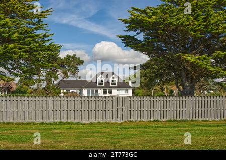Großes Haus an der Küste in East Preston in der Nähe von Littlehampton in West Sussex, England. Blick vom Strand mit Gras und Zaun davor. Stockfoto