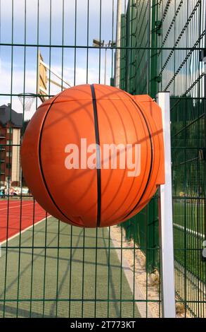 Plastikmülldose in Form eines Basketballballs auf einem Sportplatz Stockfoto