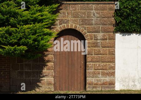 Holztür aus Ziegelstein und Blockwand. Führt zu Garten und Haus in Strandanlage. East Preston in der Nähe von Littlehampton in West Sussex, England. Stockfoto