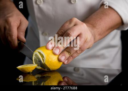 Nahaufnahme einer Koch-Hände schneiden eine Zitrone Stockfoto