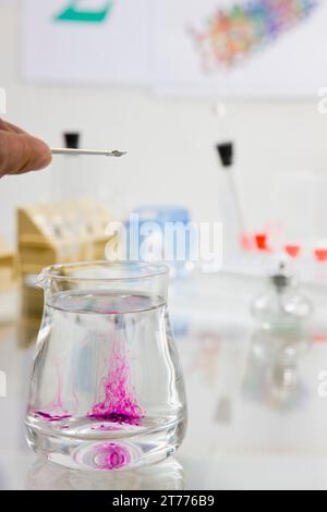 Man Finger Gießen chemische Lösung in einem Glasbehälter Stockfoto