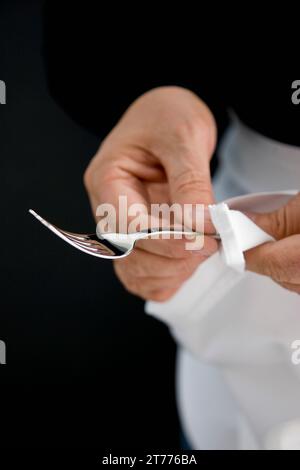 Nahaufnahme von einem Kellner Hände eine silberne Gabel mit einem weißen Tuch polieren Stockfoto