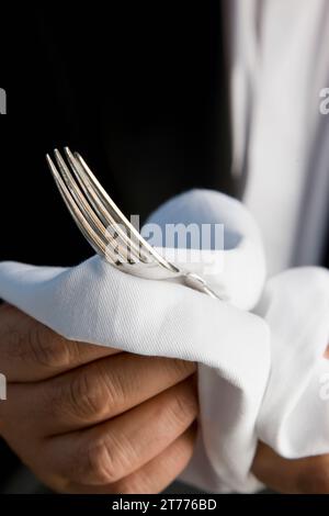 Nahaufnahme von einem Kellner Hände eine silberne Gabel mit einem weißen Tuch polieren Stockfoto