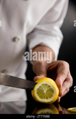 Nahaufnahme einer Koch-Hände schneiden eine Zitrone Stockfoto