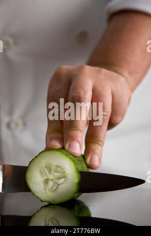 Nahaufnahme einer Koch-Hand schneiden eine Gurke Stockfoto