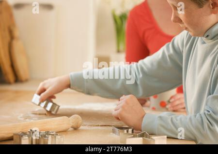 Junge, der ausgerolltes Gebäck mit einem Keksschneider schneidet Stockfoto