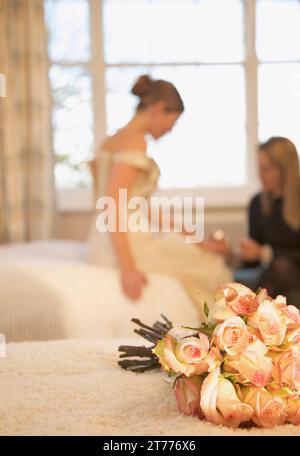 Nahaufnahme von einem Strauß Rosen auf einem Bett liegend mit Braut empfangen eine Maniküre Stockfoto