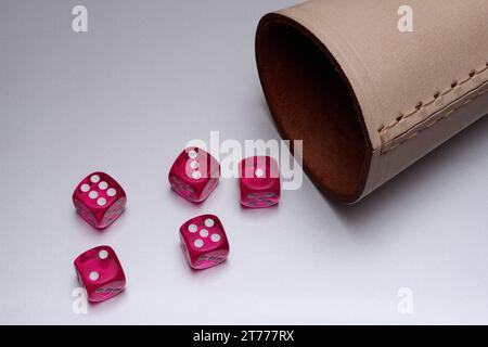 Roter Würfel und Lederbecher auf weißem Hintergrund Stockfoto