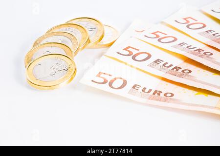 Krise der Eurozone, Details einiger Euro-Münzen auf 50-Euro-Banknoten auf weißem Hintergrund Stockfoto