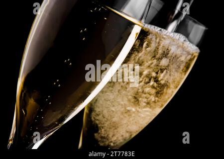 Champagner wird in eine Flöte vor schwarzem Hintergrund gegossen Stockfoto