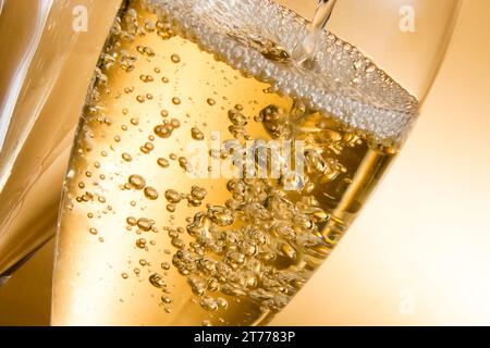 Leere Gläser Champagner und eines vor goldenem Hintergrund gefüllt Stockfoto