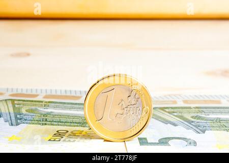 Eine Euro-Münze in der Nähe von Banknoten auf Holztisch Stockfoto