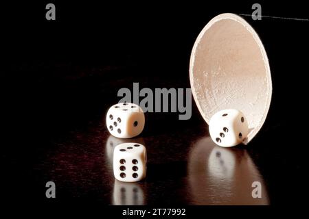 Weiße Würfel in der Nähe des Behälters auf dem alten Holztisch Stockfoto