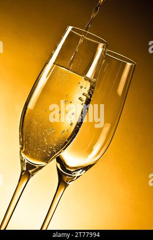 Leere Gläser Champagner und eines vor goldenem Hintergrund gefüllt Stockfoto