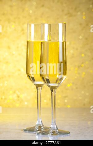 Ein Paar Sektflöten auf goldenem Bokeh-Hintergrund auf dem Tisch Stockfoto