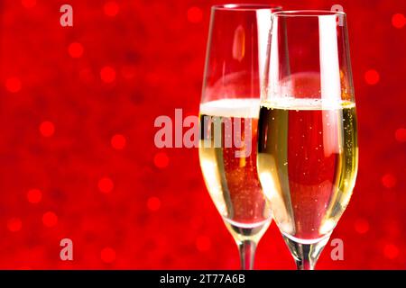 Ein Paar Sektflöten auf rotem Bokeh-Hintergrund mit Platz für Text Stockfoto
