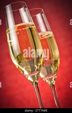 Ein Paar Flöten aus goldenem Champagner auf rotem Hintergrund Stockfoto