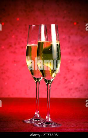 Ein Paar Sektflöten auf rotem Bokeh-Hintergrund und rotem Tisch Stockfoto