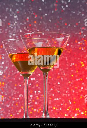 Blick von unten auf Cocktailgläser auf rotem, hellem Bokeh-Hintergrund auf dem Bartisch Stockfoto