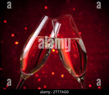 Zwei Sektflöten bejubeln auf rotem, dunklem Bokeh-Hintergrund, valentinstag- und weihnachtsveranstaltungen Stockfoto