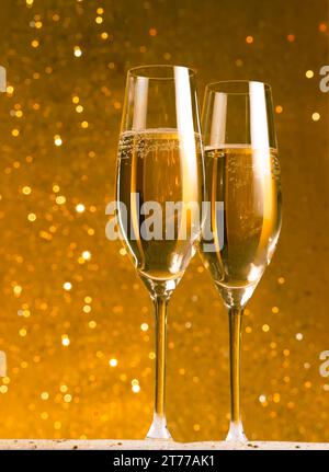 Ein Paar Sektflöten auf goldenem Bokeh-Hintergrund auf dem Tisch Stockfoto