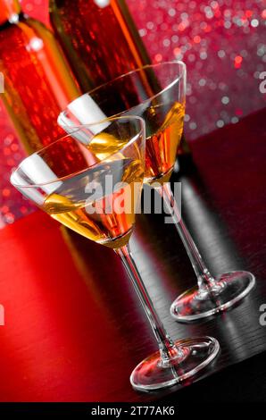 Cocktailgläser auf dem Bartisch vor Flaschen auf rotem, hellem Bokeh-Hintergrund Stockfoto