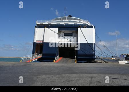 Öffnen Sie die Heckrampe und die hinteren Türen, um Autos zu beladen und Passagiere auf eine große Fähre mit blauem und weißem Rumpf zu befördern. Stockfoto