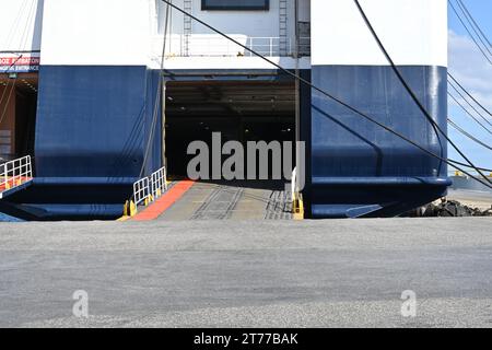 Offene Hecktüren und Heckrampe für das Verladen von Autos und das Einsteigen von Fahrgästen auf eine große Fähre mit blauem und weißem Rumpf. Stockfoto