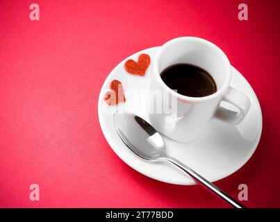 Dekorative rote Herzen in der Nähe einer Tasse Kaffee auf rotem Tisch mit Platz für Text, Konzept valentinstag Stockfoto