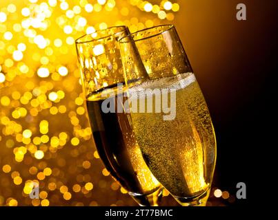 Detail der Sektflöten mit goldenen Blasen auf dunklem goldenem heller Bokeh-Hintergrund mit Platz für Text Stockfoto