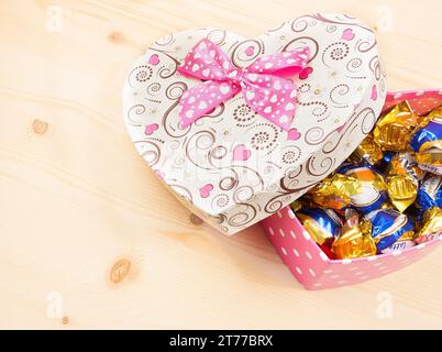 Schokoladenbonbons in Geschenkbox auf Holztisch mit Platz für Text, valentinstag-Konzept Stockfoto