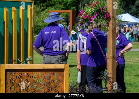 4 Freiwillige stehen zusammen, um den Wettbewerb „Talk by Empowerment Garden“ zu präsentieren - Sunny RHS Tatton Park Flower Show 2023, Cheshire, England, Großbritannien. Stockfoto