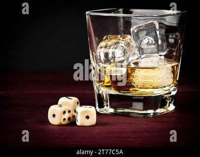 würfel in der Nähe von Whiskey-Glas auf alten Holztisch, Spielkonzept Stockfoto