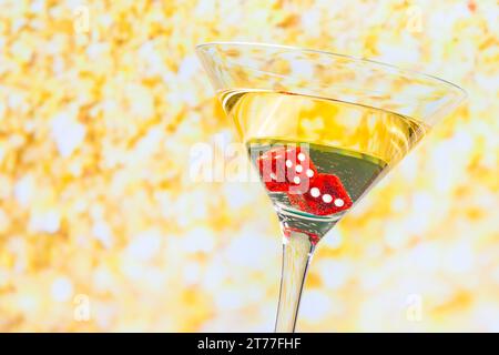 Rote Würfel im Cocktailglas auf goldenem Hintergrund Stockfoto