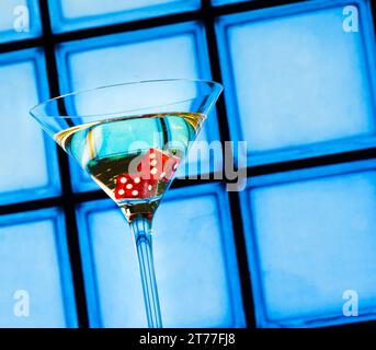 Rote Würfel im Cocktailglas auf blauem Hintergrund Stockfoto