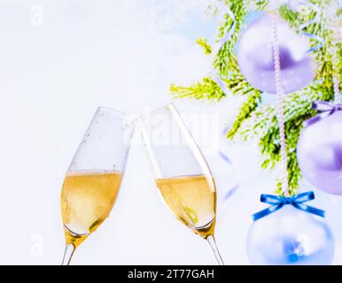Champagnerflöten mit goldenen Blasen machen Anfeuerungen auf dem Hintergrund der weihnachtsbaumdekoration, weihnachtliche Atmosphäre Stockfoto