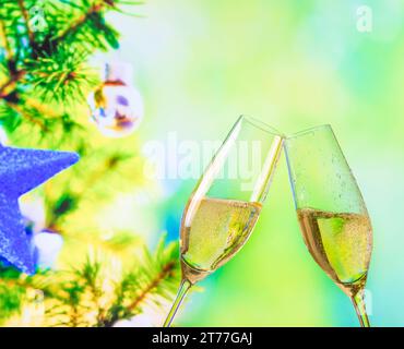 Champagnerflöten mit goldenen Blasen machen Anfeuerungen auf dem Hintergrund der weihnachtsbaumdekoration, weihnachtliche Atmosphäre Stockfoto