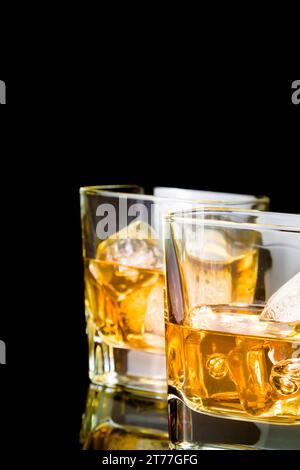 Whiskey mit Eis in Gläsern auf schwarzem Hintergrund, mit Reflexion Stockfoto