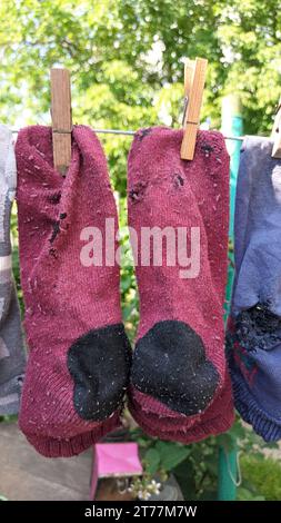 Sauber gewaschene alte, genähte, schäbige Socken hängen im Sommer draußen am Draht Stockfoto