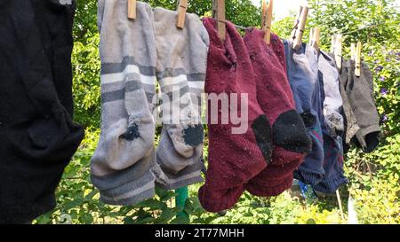 Sauber gewaschene alte, genähte, schäbige Socken hängen im Sommer draußen am Draht Stockfoto