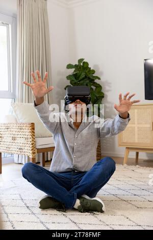 Birassischer Mann mit vr-Headset, der zu Hause den virtuellen Bildschirm berührt Stockfoto